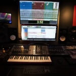 A recording studio with a keyboard, monitor and computer.