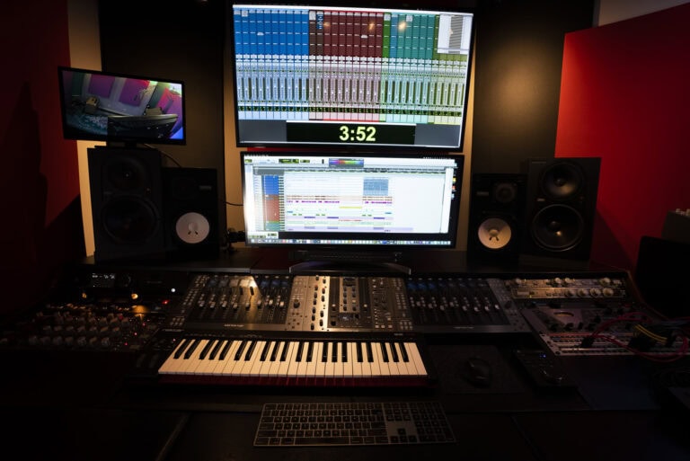 A recording studio with a keyboard, monitor and computer.