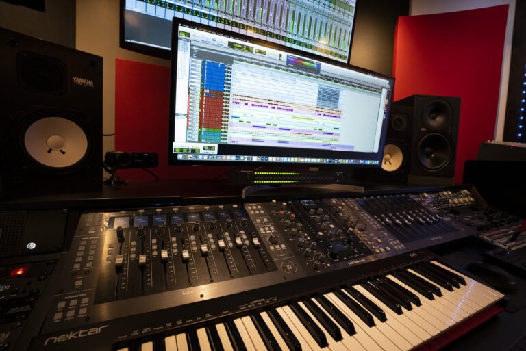 A music studio with a keyboard, monitor and computer.